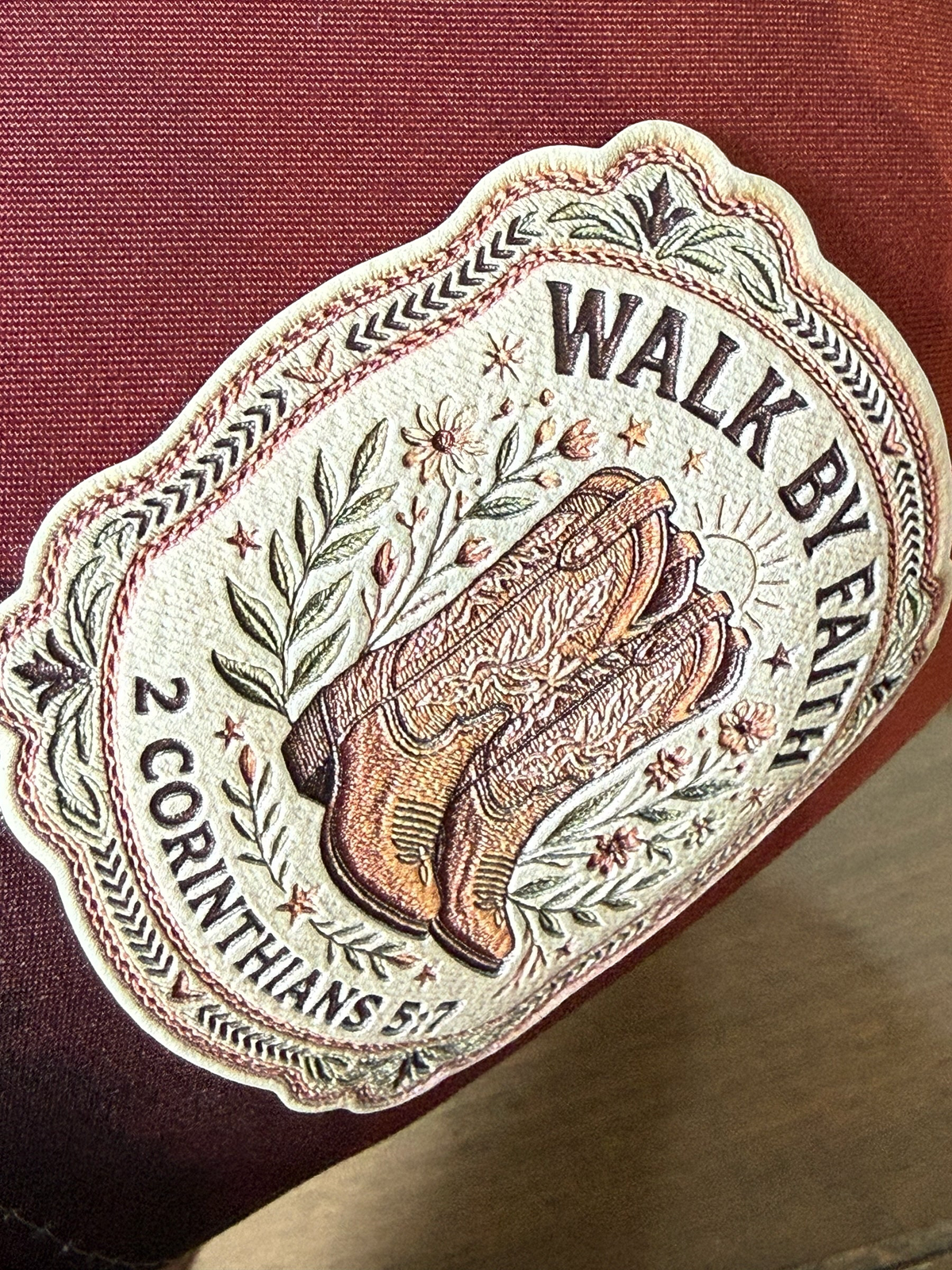 Moss & Maple Signs and Designs trucker hat featuring an embroidered patch of cowboy boots, flowers, and scripture.