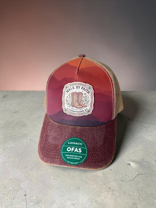 Moss & Maple Signs and Designs trucker hat with sunset mountain print, cowboy boot patch, and mesh back.